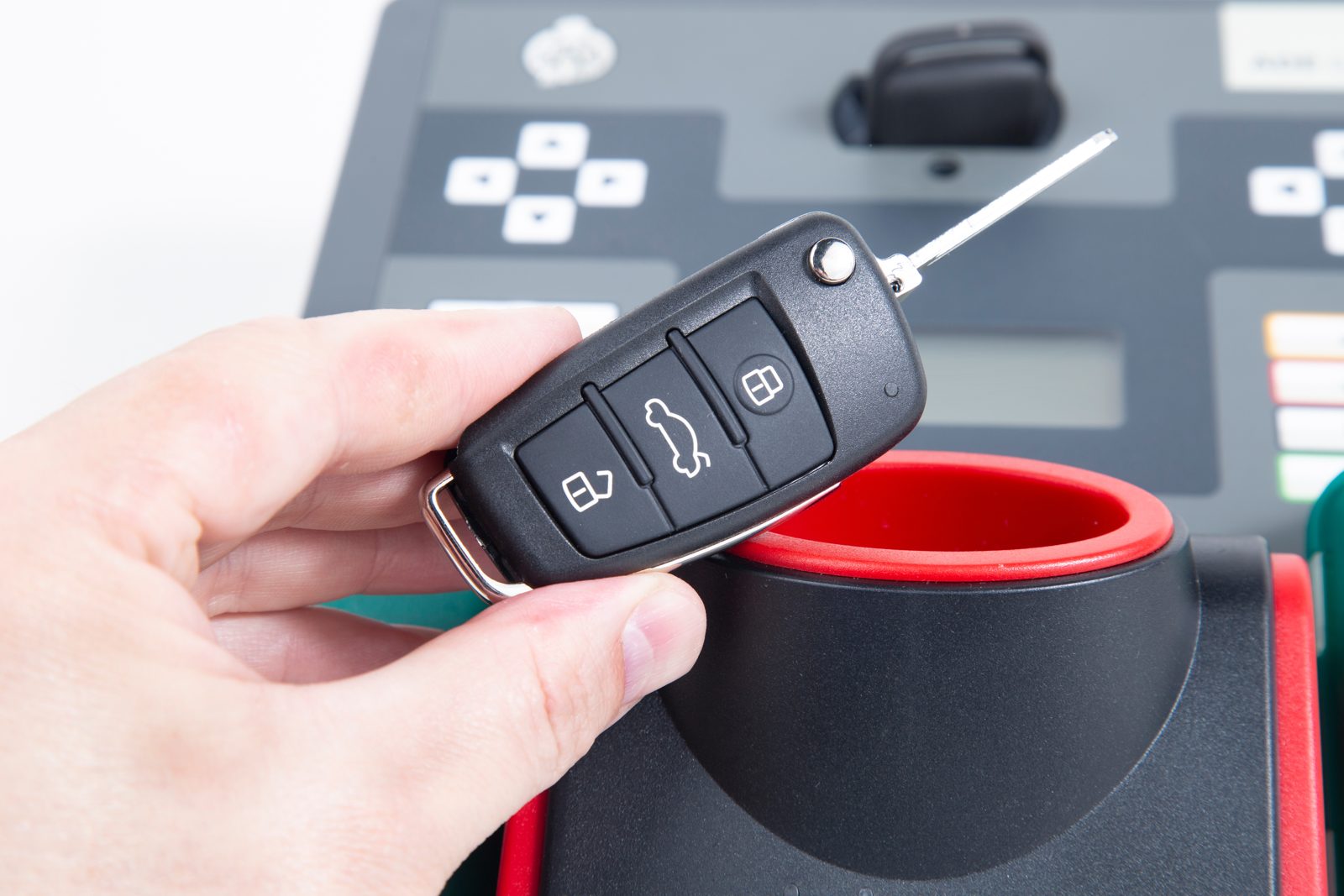 Locksmith holding a programmed car key fob at a key programming machine in Washington, DC